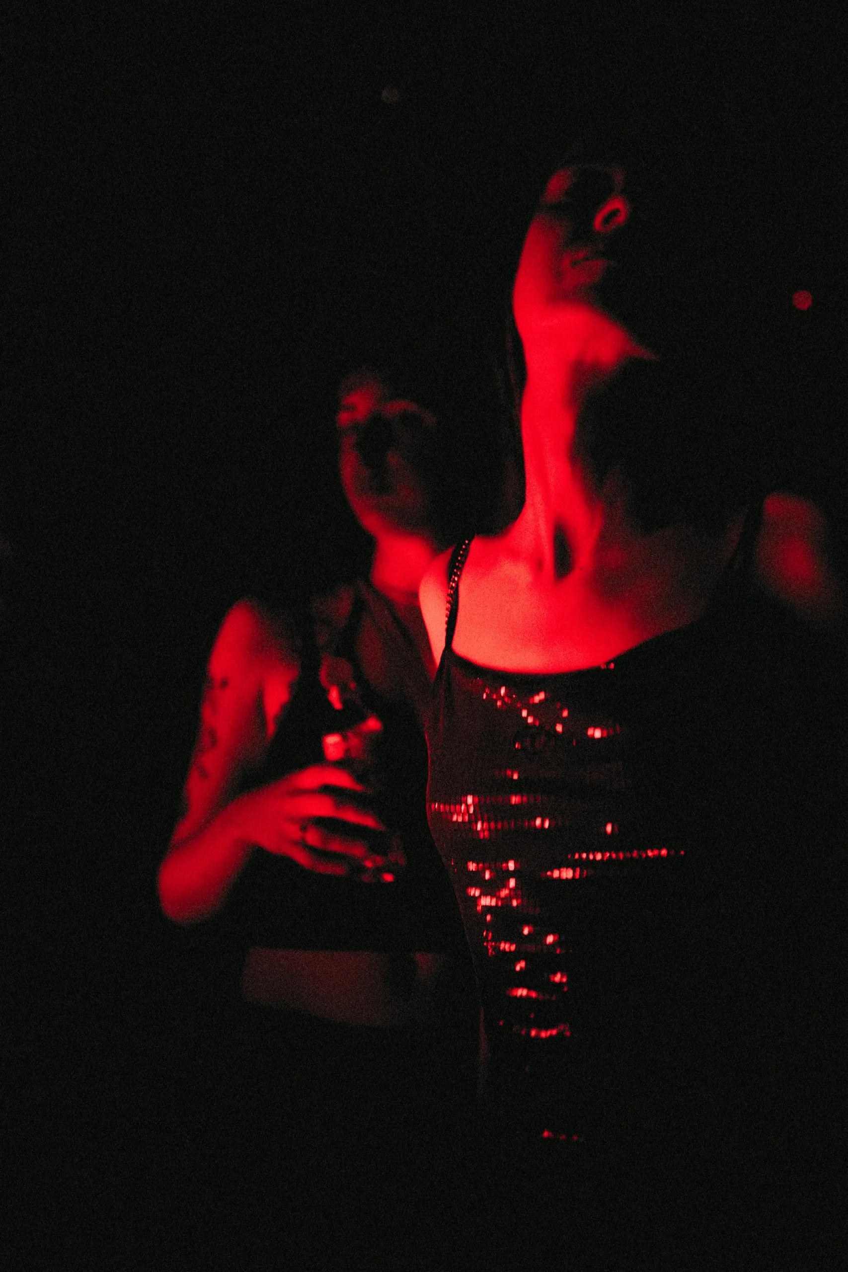 Chica con top de lentejuelas mirando hacia la luz, junto a una amiga