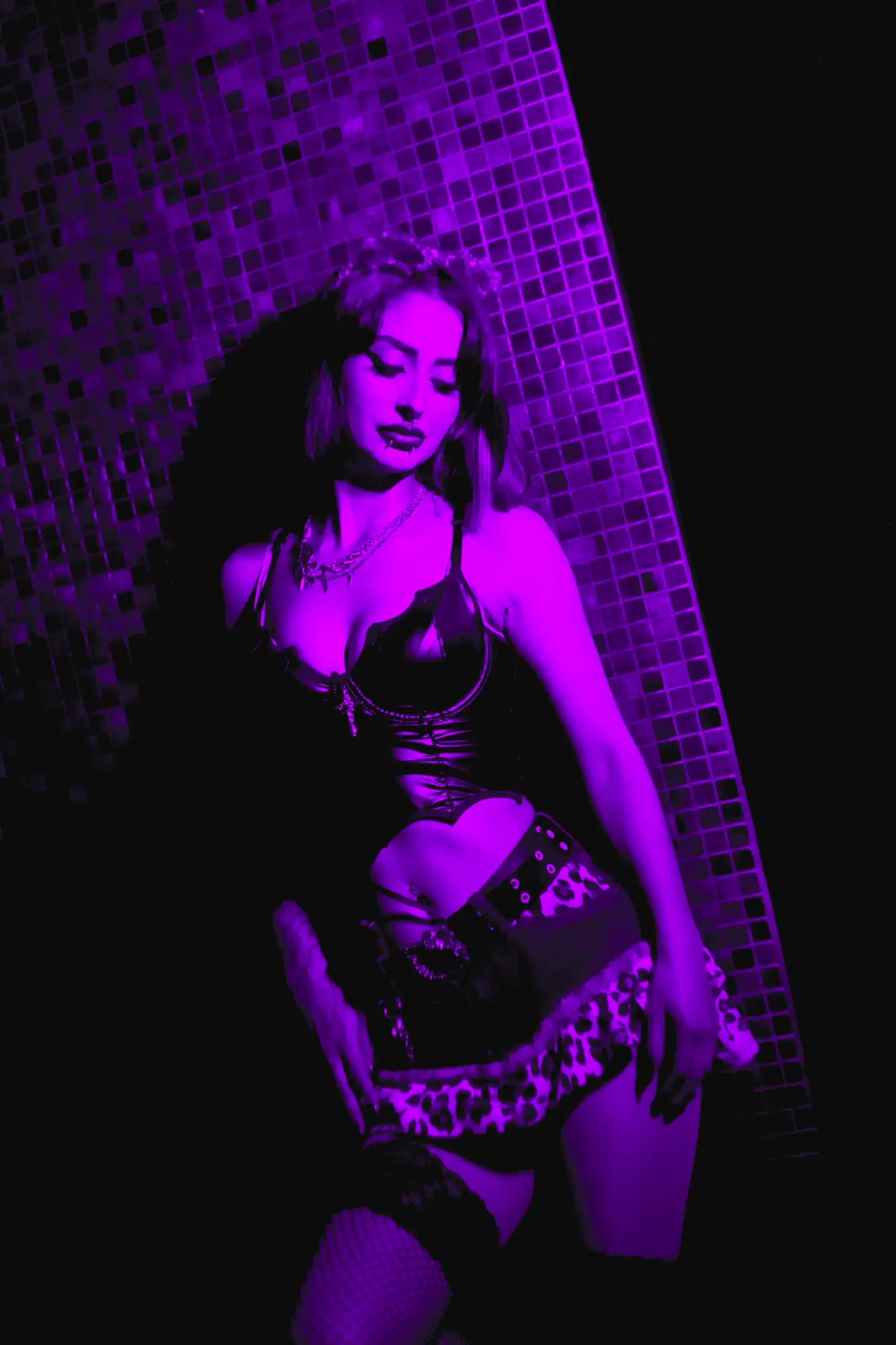 Chica posando junto a una pared de azulejos bajo luz morada