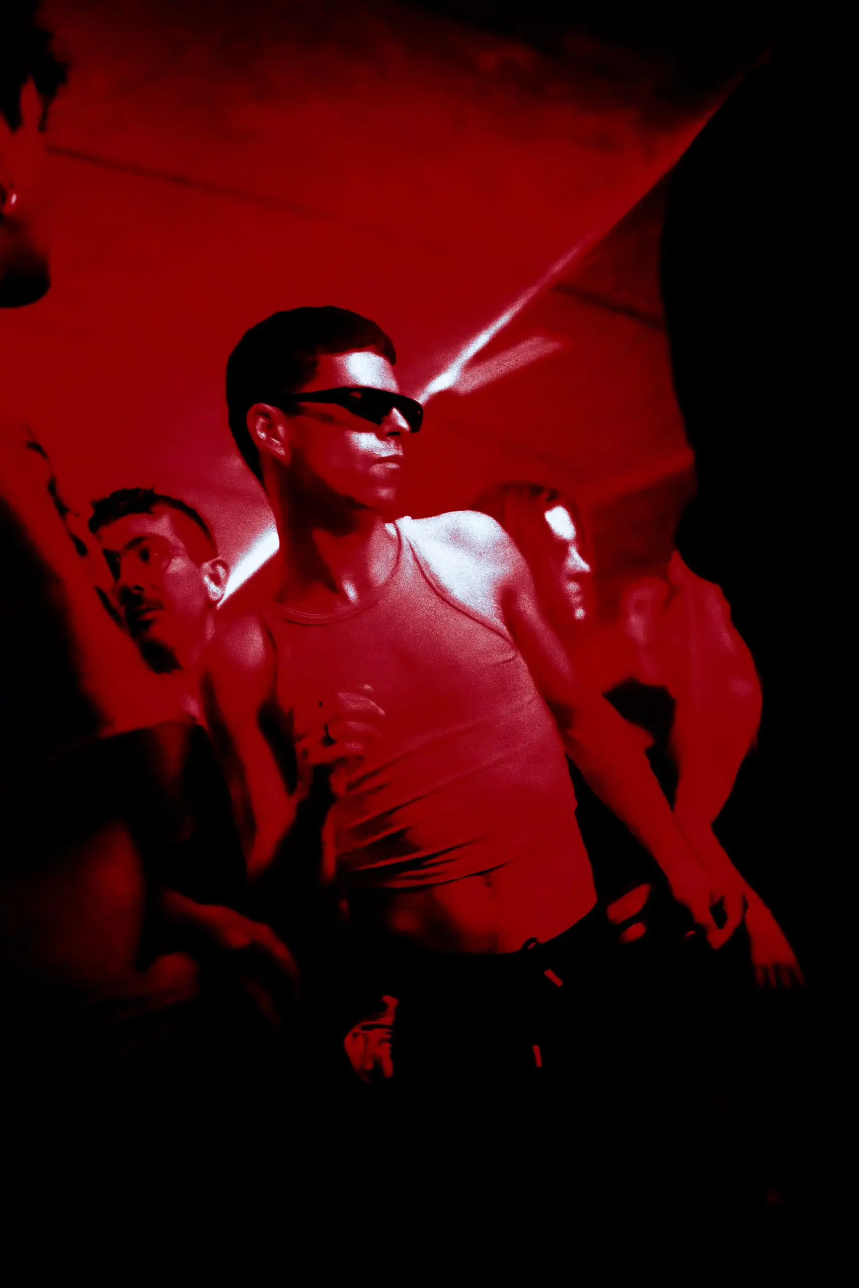 Chico con gafas de sol bailando bajo luz roja